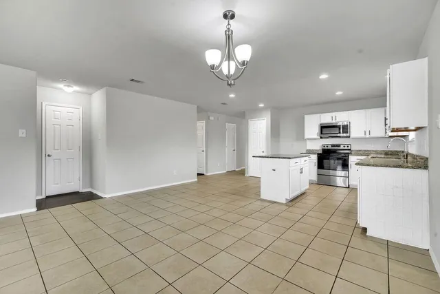 a kitchen with stainless steel appliances granite countertop a refrigerator a stove a oven and white cabinets with wooden floor