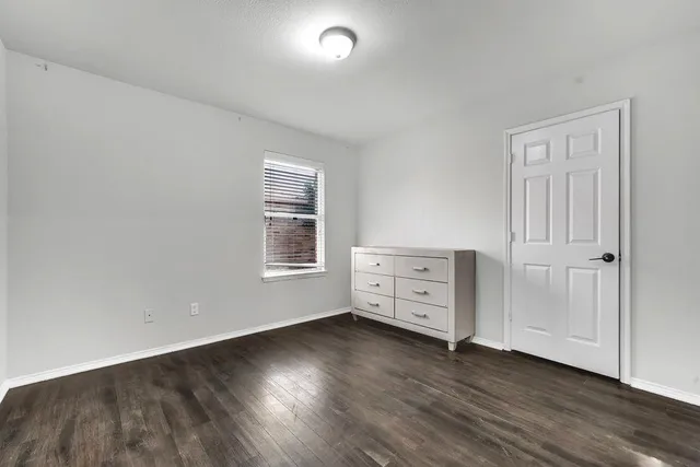 an empty room with wooden floor and cabinet