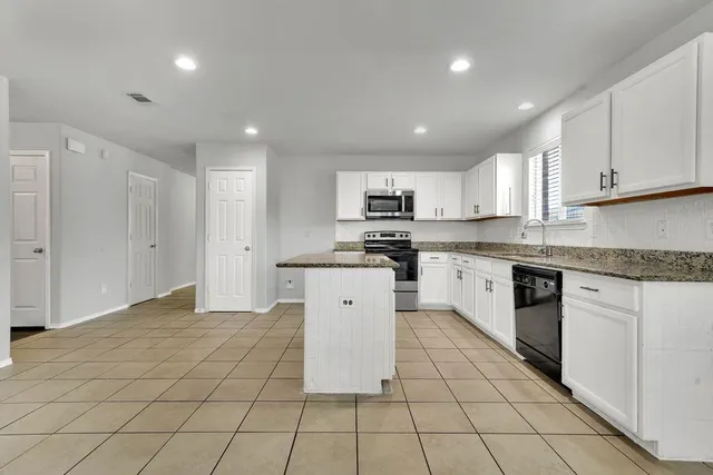a kitchen with a sink a white cabinets and appliances