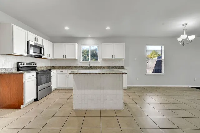 a kitchen with stainless steel appliances granite countertop a stove top oven a sink a counter top space cabinets and a window