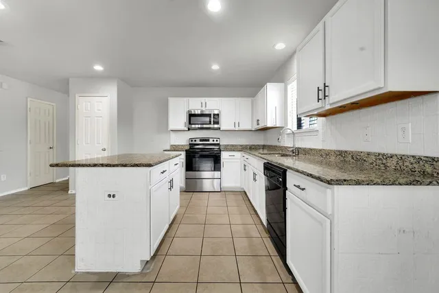 a kitchen with granite countertop white cabinets white stainless steel appliances with a sink and dishwasher