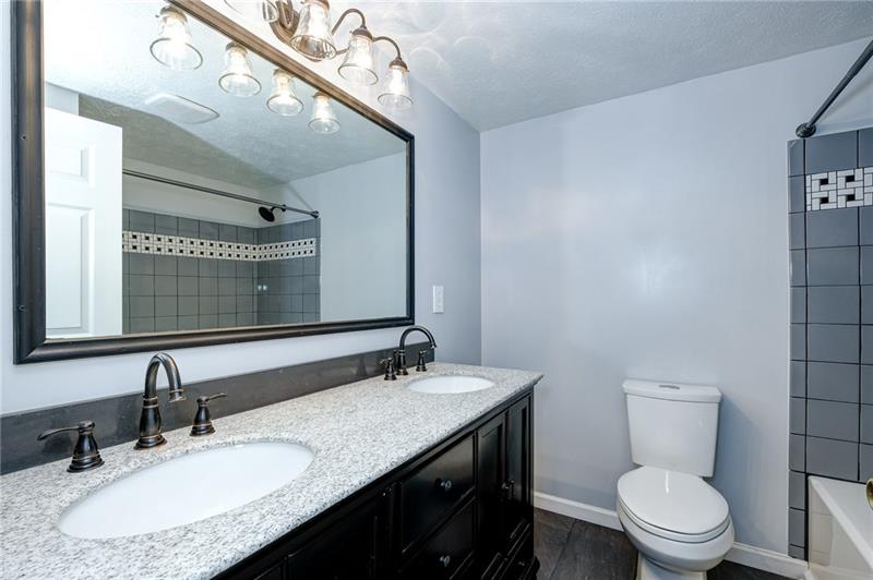 402 Three Degree Road Renfrew, PA 16053 - Photo 18 of 25 Gorgeous hall bathroom with double stone sinks, new floors, commode, fixtures, and tiled shower.