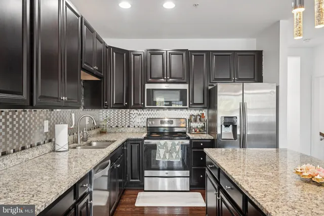 a kitchen with stainless steel appliances granite countertop a sink stove and refrigerator