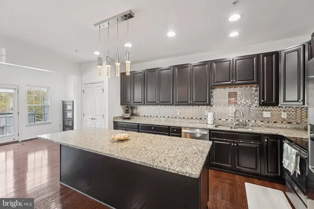 a kitchen with kitchen island granite countertop a sink stove and cabinets