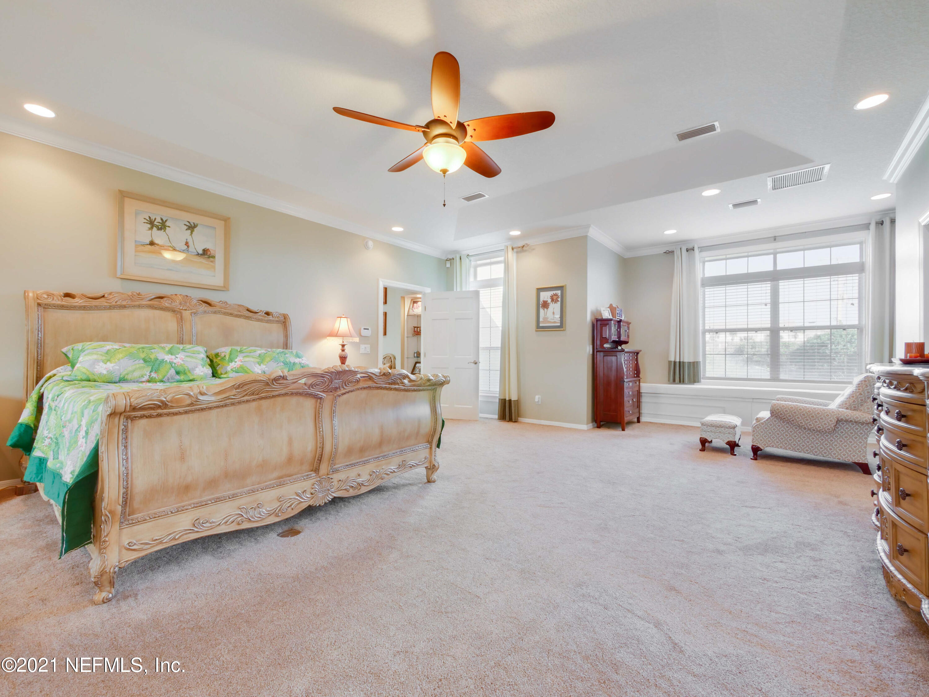 8115 A1A South St. Augustine, FL 32080 - Photo 23 of 50 a spacious bedroom with a bed a dresser and a chandelier