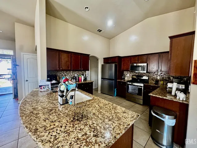 a kitchen with stainless steel appliances kitchen island granite countertop a refrigerator and a stove top oven
