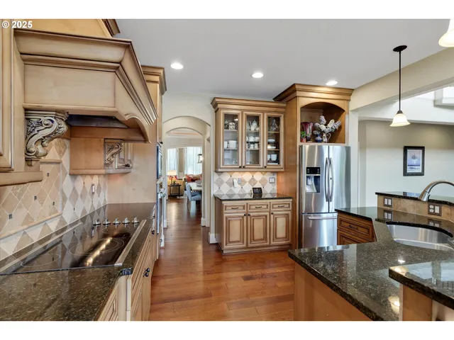 a kitchen view with stainless steel appliances granite countertop a sink a stove and a wooden floors