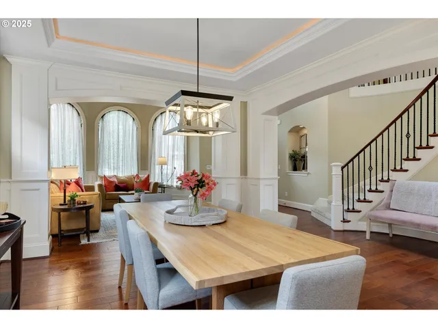 a dining room with wooden floor a chandelier a wooden table and chairs