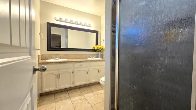 a bathroom with a granite countertop shower a sink and a toilet