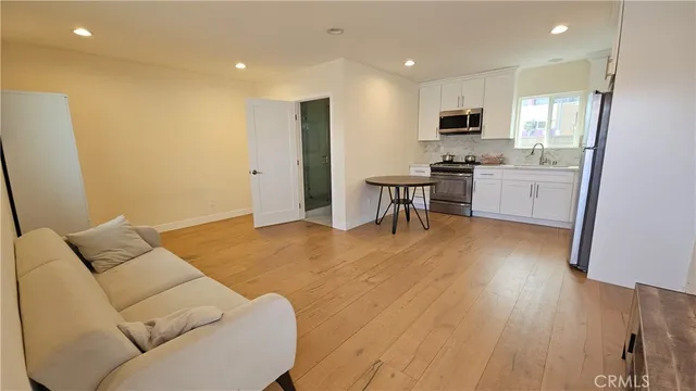 a living room with stainless steel appliances furniture and a wooden floor