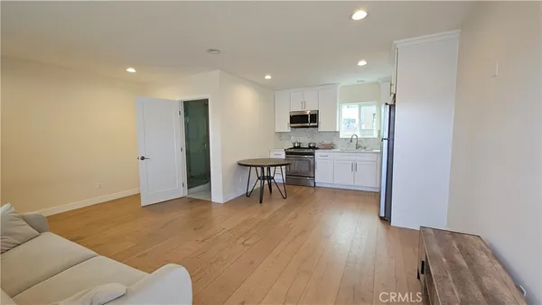 a living room with stainless steel appliances kitchen island furniture and wooden floor