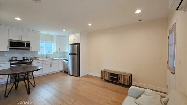 a kitchen with stainless steel appliances granite countertop a refrigerator a stove a sink a microwave a dining table and chairs with wooden floor