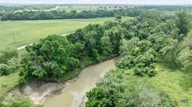 an aerial view of green landscape with trees houses and lake view