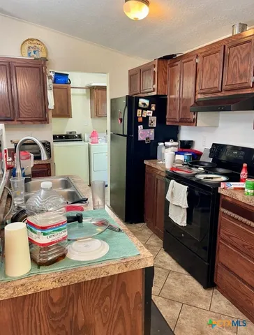 a kitchen with granite countertop lots of clutter and stainless steel appliances