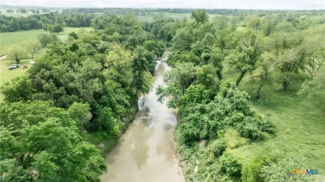 an aerial view of residential house with outdoor space and trees all around