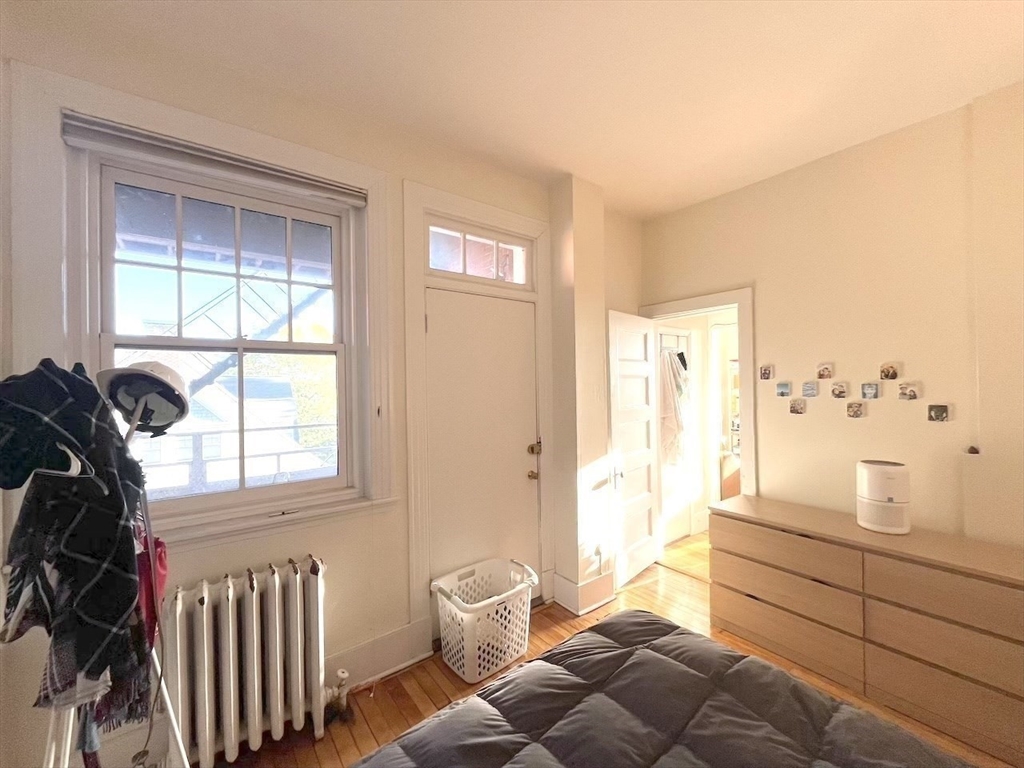 371 Harvard Street, Unit 3C Cambridge, MA 02138 - Photo 19 of 27 a bedroom with a bed and wooden floor