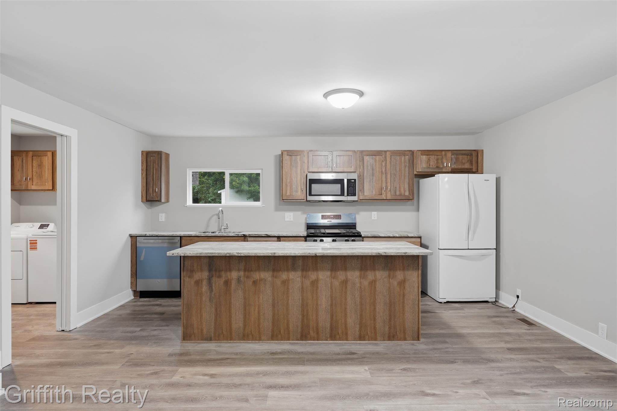5820 Mack Road Howell, MI 48855 - Photo 15 of 60 Kitchen featuring wood-finish cabinetry, stainless steel appliances, a center island with counter seating, and wood-finish flooring