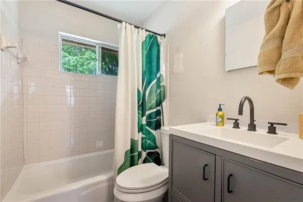 a bathroom with a sink a toilet a window and shower