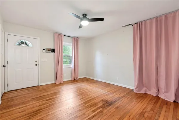 an empty room with wooden floor fan and windows