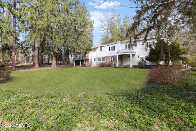 59 Cherry Valley Road Greenwich, CT 06831 - Photo 2 of 19 a view of a white house in front of a big yard with plants and large trees