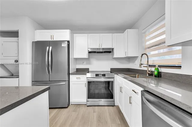 a kitchen with granite countertop a refrigerator stove top oven and sink