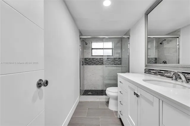 a bathroom with a sink a toilet a mirror and shower