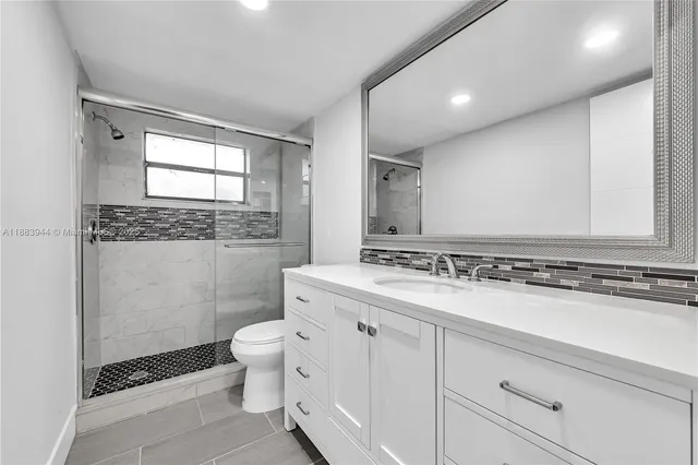 a bathroom with a granite countertop sink a toilet and a mirror
