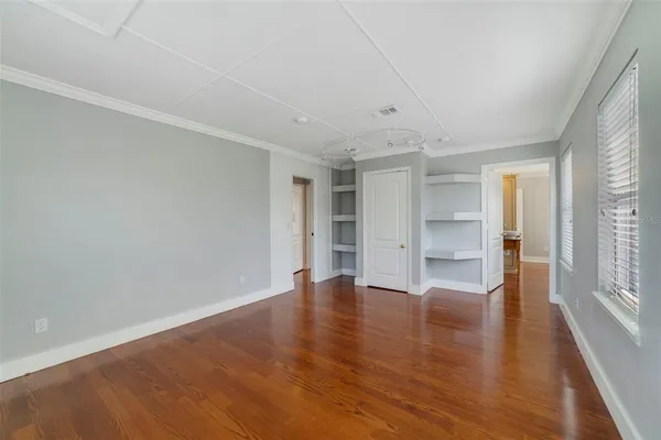 a view of an empty room with a window and wooden floor