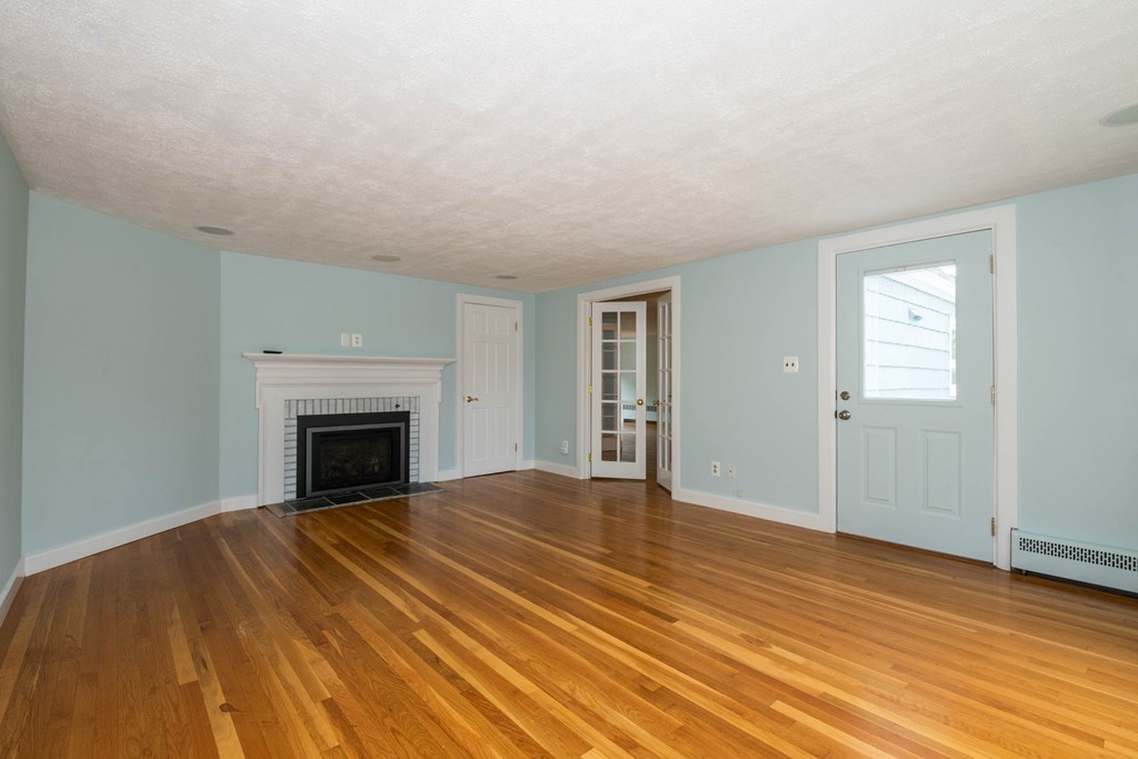 27 Margaret Road Hamilton, MA 01982 - Photo 11 of 30 a view of empty room with wooden floor and fireplace