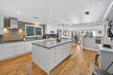 a large kitchen with stainless steel appliances granite countertop a lot of counter space and wooden floors
