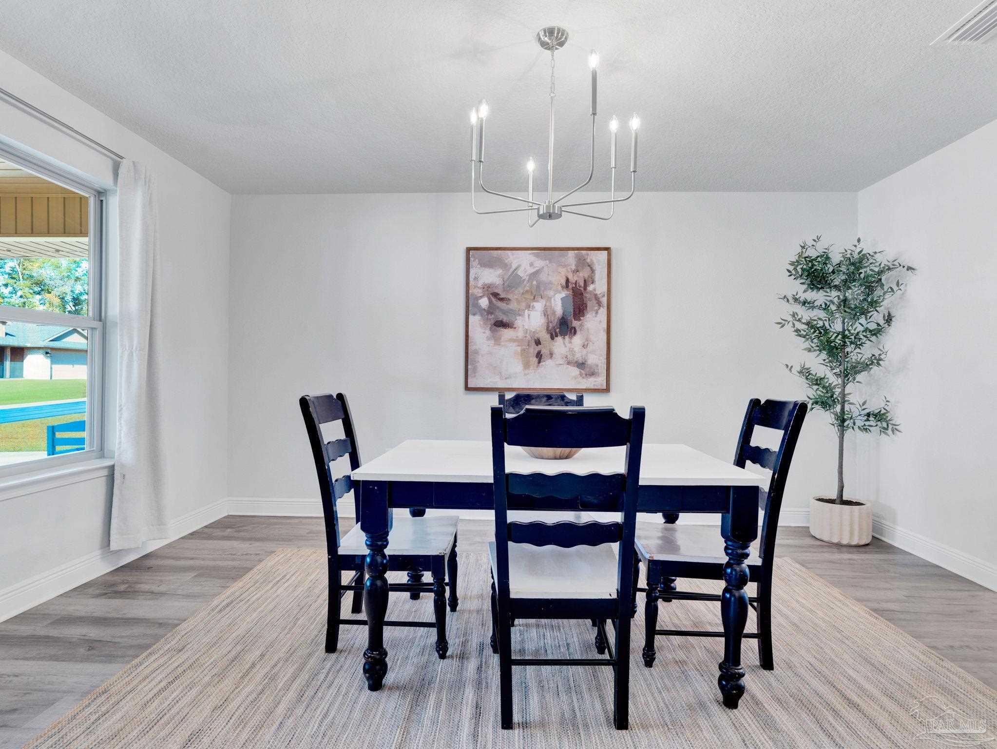 5956 Parsonage Circle Milton, FL 32570 - Photo 20 of 66 a dining room with furniture potted plants and wooden floor