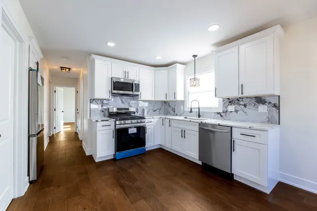 a kitchen with granite countertop white cabinets and stainless steel appliances