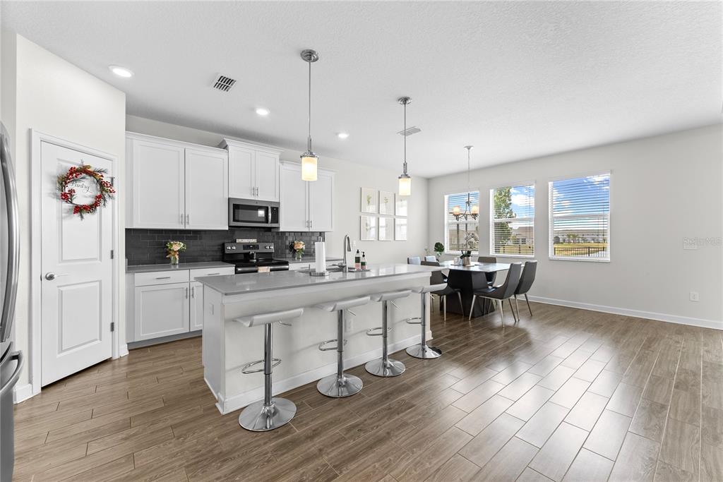 2926 Wordsmith Road Kissimmee, FL 34746 - Photo 19 of 42 a kitchen with stainless steel appliances granite countertop a stove top oven a sink a dining table and chairs with wooden floor