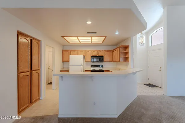 a large kitchen with stainless steel appliances a large counter top a sink a stove and a refrigerator