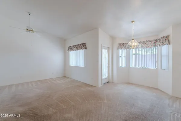 a view of an empty room with chandelier fan and window