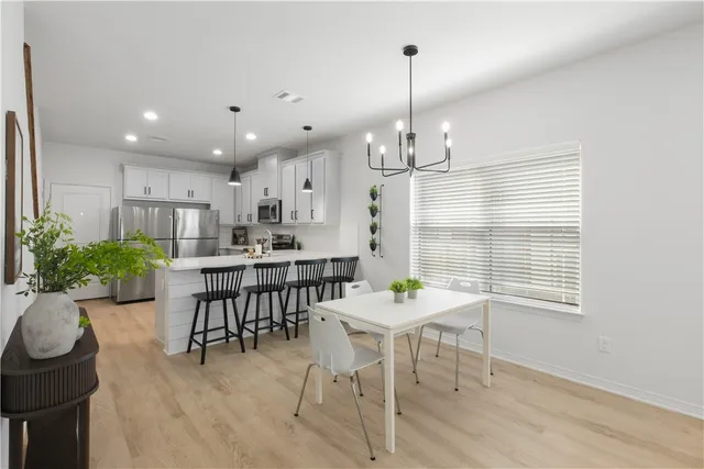 a view of a dining room and livingroom with furniture wooden floor a chandelier