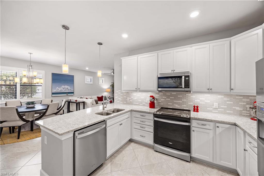 7658 Jacaranda Lane Naples, FL 34114 - Photo 8 of 30 Kitchen with stainless steel appliances, a peninsula, white cabinets, under cabinet lighting, Quartz countertops