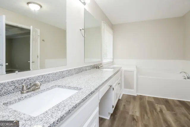 a bathroom with a granite countertop double vanity sink and mirror
