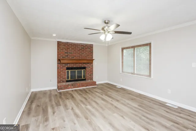 a view of an empty room with window and chandelier fan
