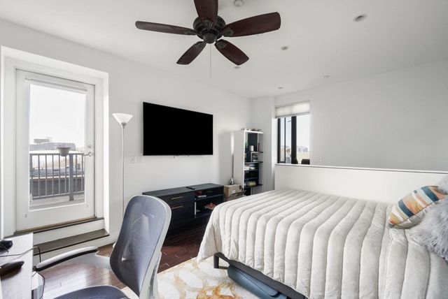 a bedroom with a bed a flat screen tv and a large window