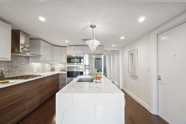 a view of a kitchen with granite countertop a sink stainless steel appliances and cabinets