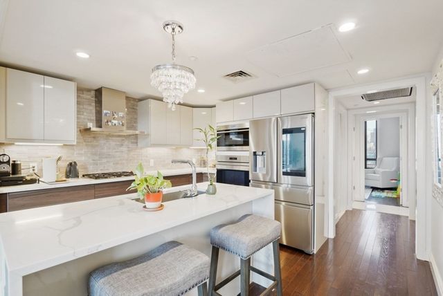 a kitchen with stainless steel appliances a dining table chairs and wooden floor