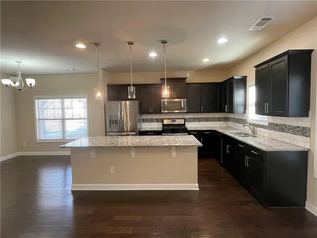 a large kitchen with stainless steel appliances kitchen island a large counter top and a stove