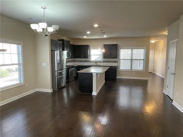 a kitchen with stainless steel appliances granite countertop a sink a stove and a wooden floors