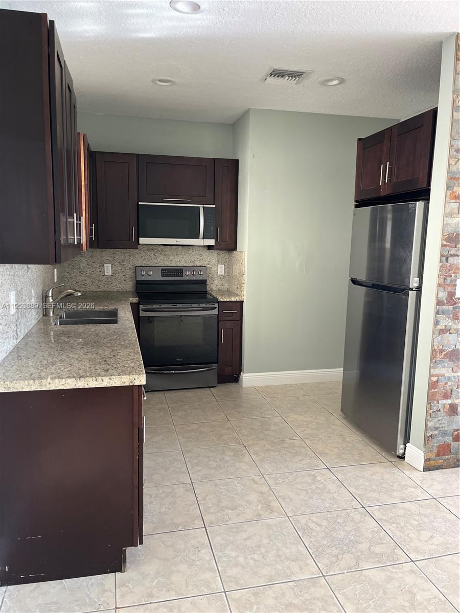 601 Northwest 97th Street, Unit 601 Miami, FL 33150 - Photo 3 of 16 a kitchen with a refrigerator sink and stove