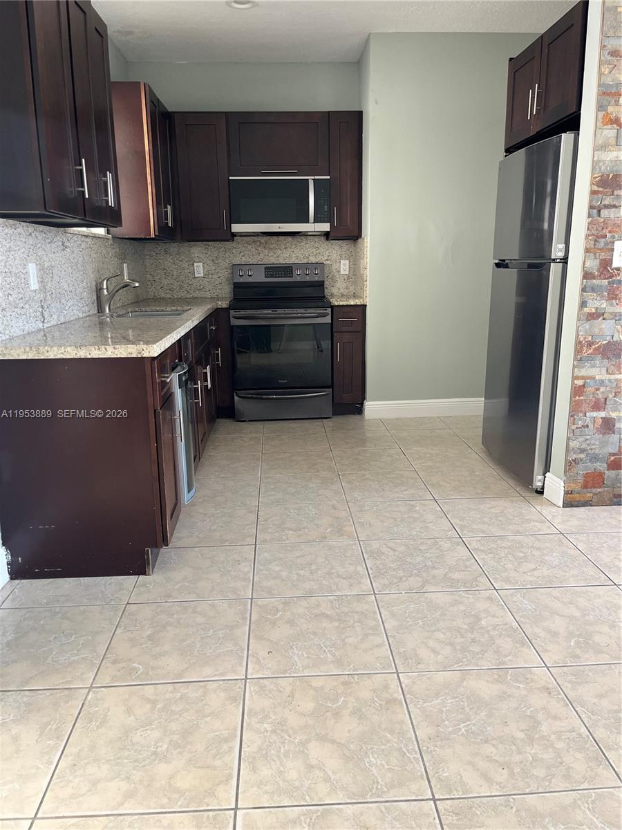 601 Northwest 97th Street, Unit 601 Miami, FL 33150 - Photo 4 of 16 a kitchen with stainless steel appliances granite countertop a refrigerator and a sink