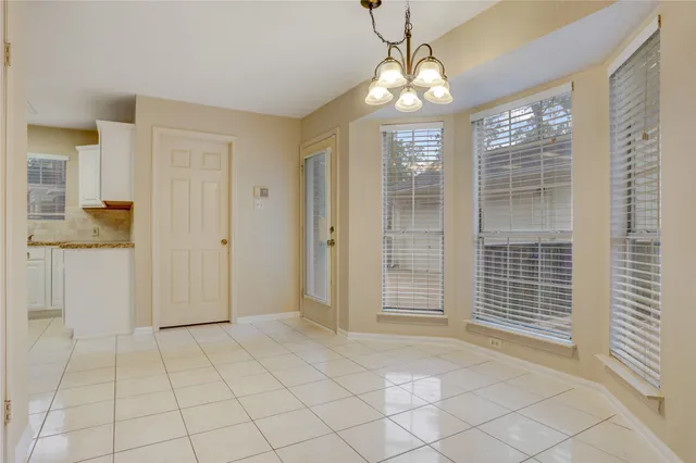 an empty room with windows fireplace and a kitchen