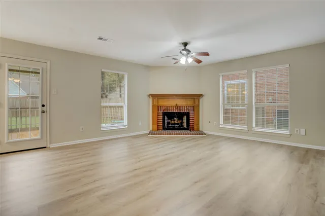 an empty room with windows and fireplace