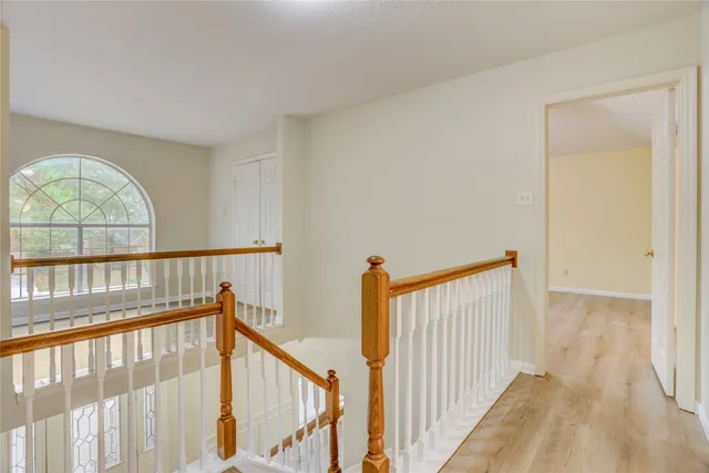an empty room with wooden floor chandelier fan and windows