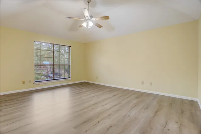 an empty room with wooden floor and fan